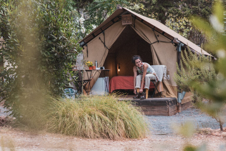 Mulher a sorrir enquanto coloca botas em frente à sua barraca Woody