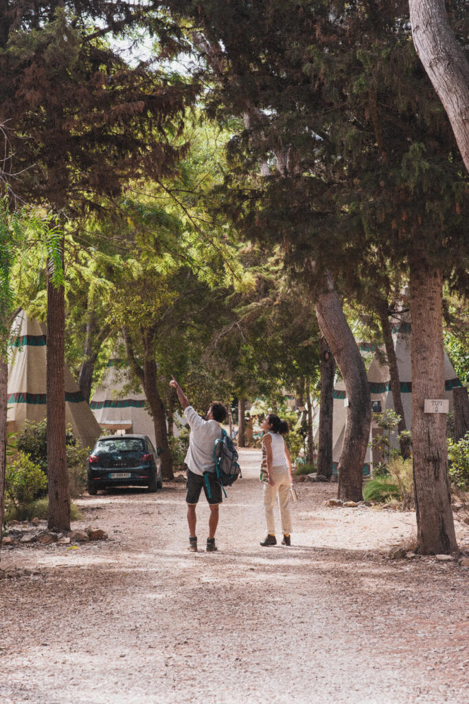 Casal a caminhar pelo caminho das cabanas tipis, felizes e a apontar para algo