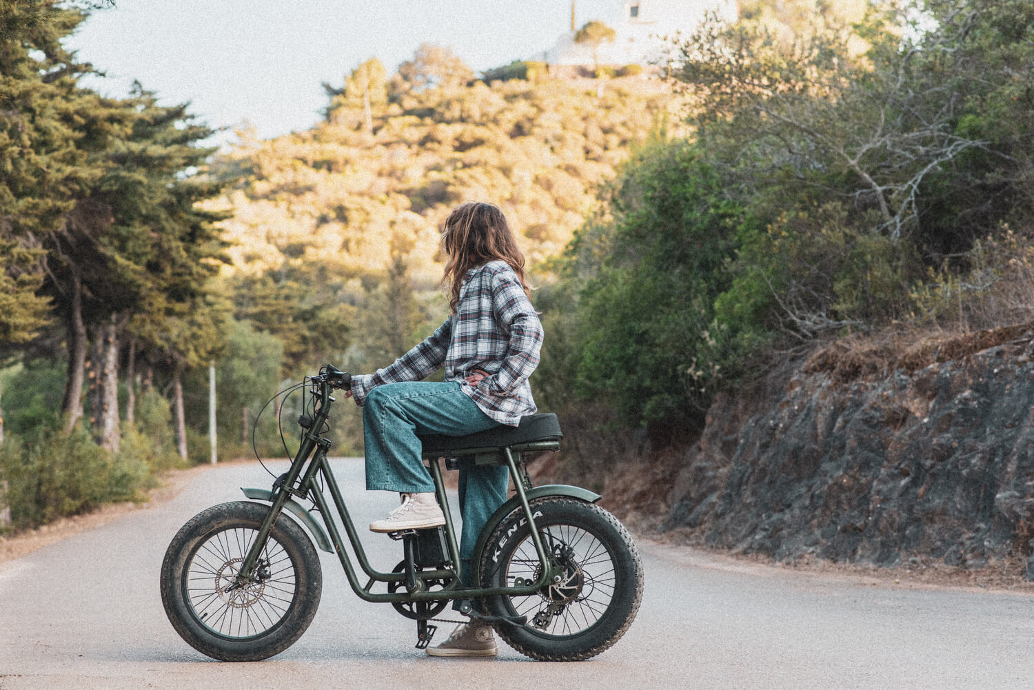 Mulher parada, a olhar a vista, em cima de uma bicicleta.