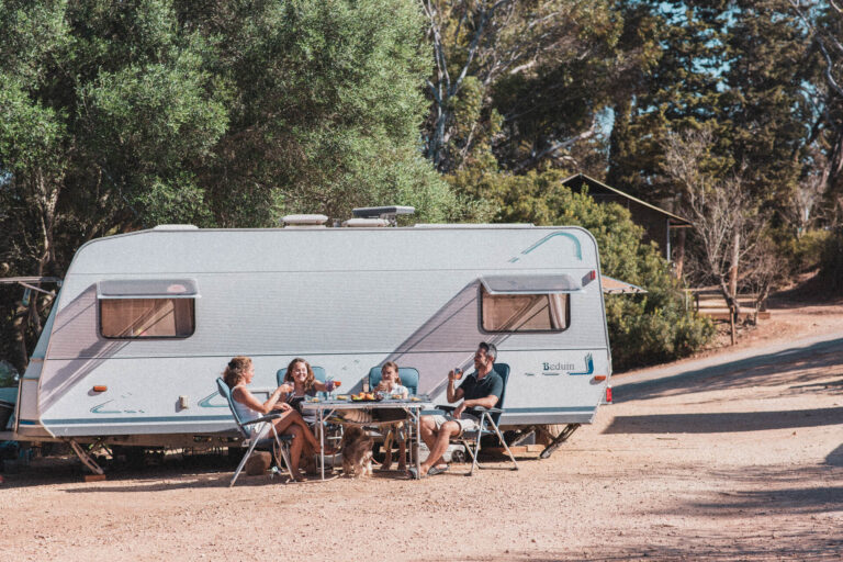 Pessoas sentadas conversando em frente a um mobile home