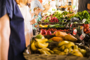 pessoas a comprar legumes no mercado de barracas