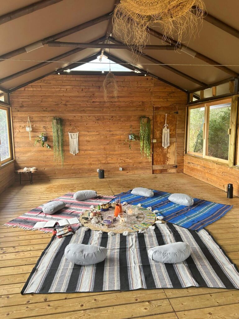 Espaço decorado para retiro, com uma roda, tapetes e travesseiros.