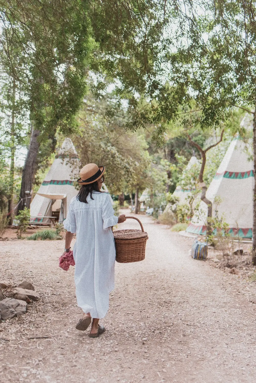 Mulher com um cesto de piquenique a caminhar pelo Salema Eco Camp.