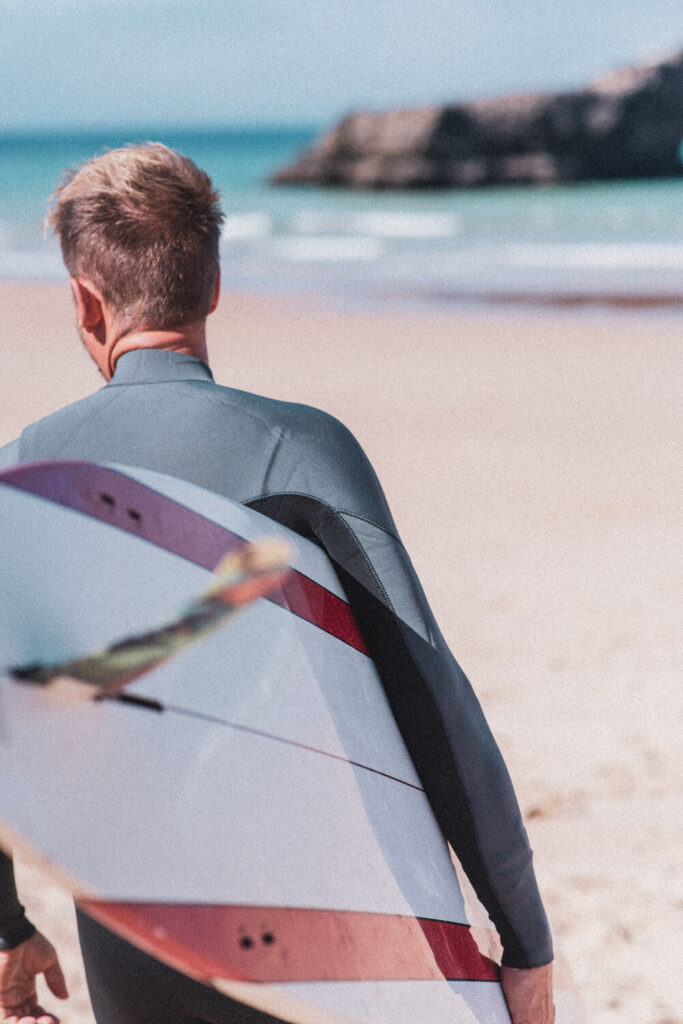Homem com uma prancha de surf numa praia